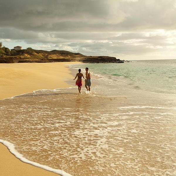 Couple marchant dans les vagues de la plage de Papohaku