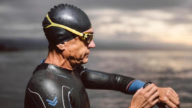 Athlète en combinaison de triathlon réglant sa montre avant l’épreuve de natation lors de l’Ironman à Kailua-Kona.