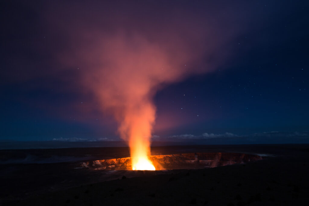 Éruption nocturne du cratère Halemaʻumaʻu au sommet du Kilauea, avec une colonne de lave incandescente illuminant le ciel étoilé