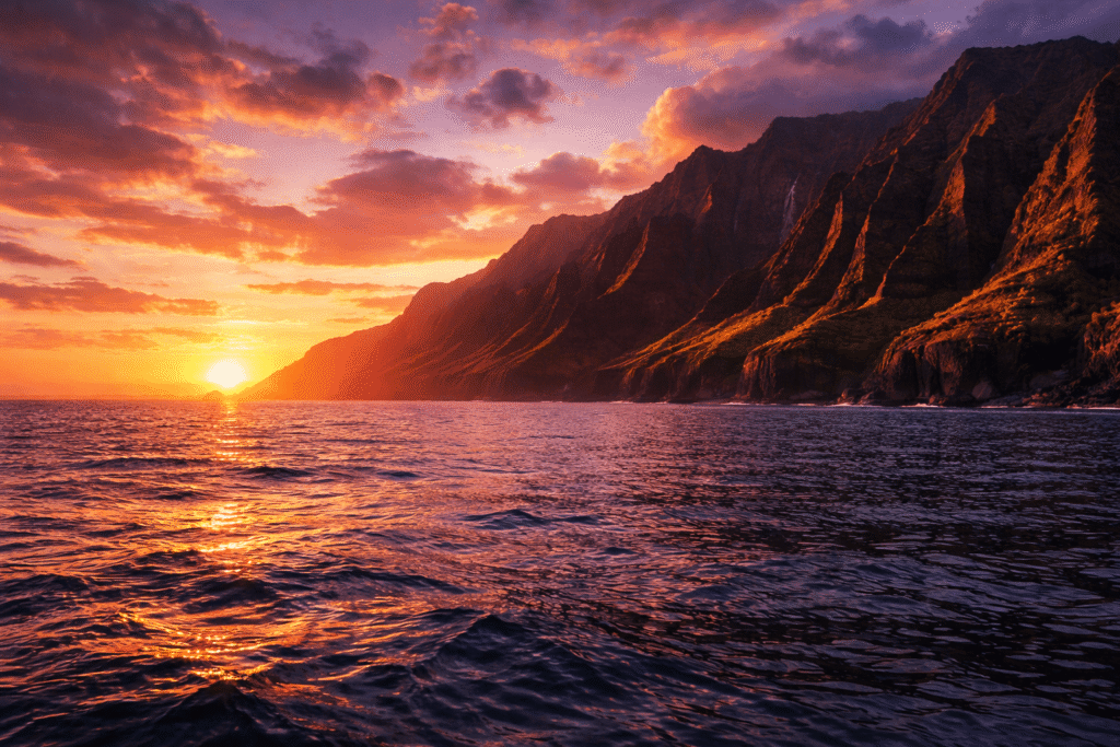Coucher de soleil doré illuminant les falaises de la Na Pali Coast avec un ciel orange et violet se reflétant sur l'océan Pacifique