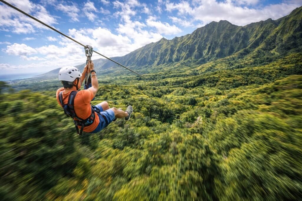 Personne glissant sur une tyrolienne au-dessus d'une vallée verdoyante à Hawaii avec des crêtes montagneuses en arrière-plan